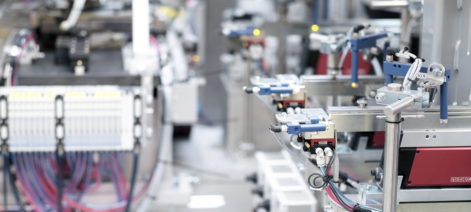 Nærbillede af industriel automatisering, der viser komplicerede maskiner, ledninger og robotkomponenter på en produktionslinje.